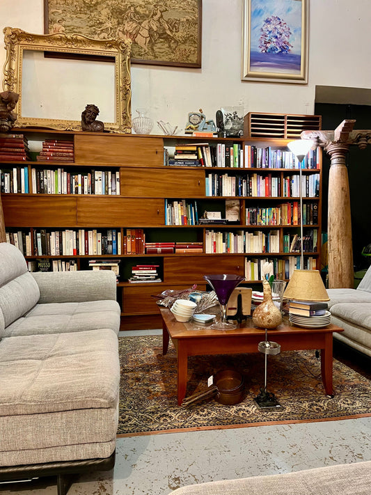 L’Histoire du Mobilier : un espace de vie avec des meubles classiques et une bibliothèque.